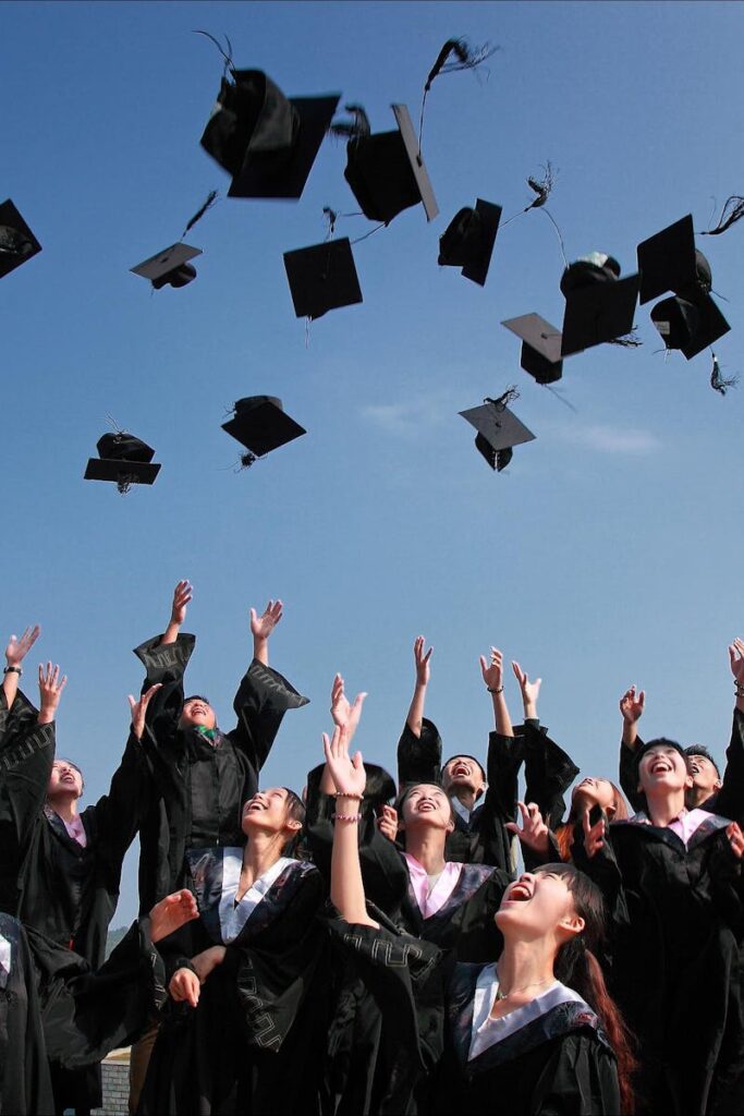 Newly Graduated People Wearing Black Academy Gowns Throwing Hats Up in the Air