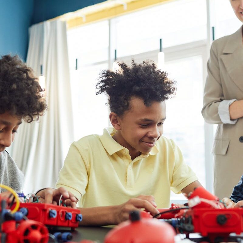 Group of Children at a Table With Plastic Toys and Electric Wires