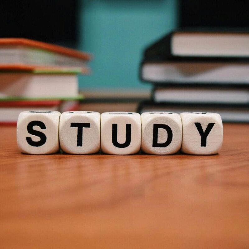 Close-up of study blocks and stacked books on a wooden desk, symbolizing education and learning.